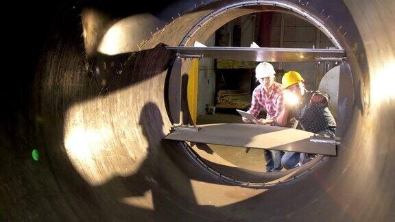 两名工人在工厂检查大型金属物体
