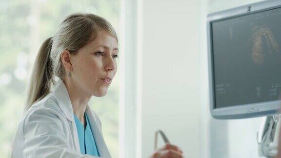 在医院里孕妇接受超声检查产科医生在电脑屏幕上检查健康婴儿的图片医生解释图片的细节