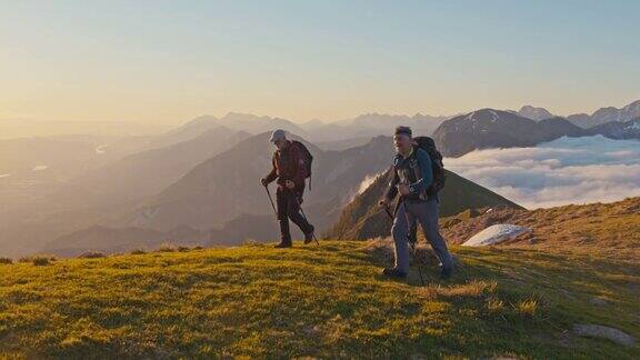 日落时分徒步旅行者在山脊上行走