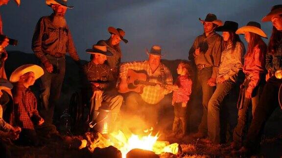 牛仔们晚上围在篝火旁看吉他表演