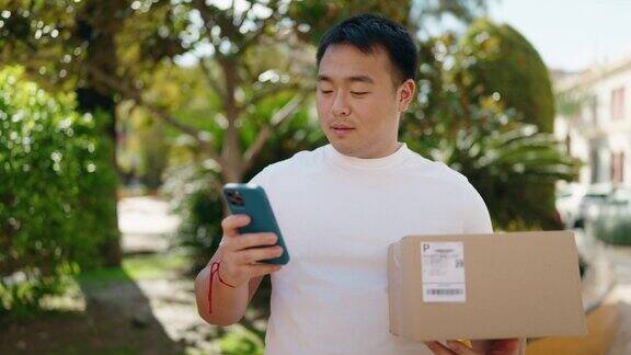 中国一名年轻男子在公园用智能手机快递包裹