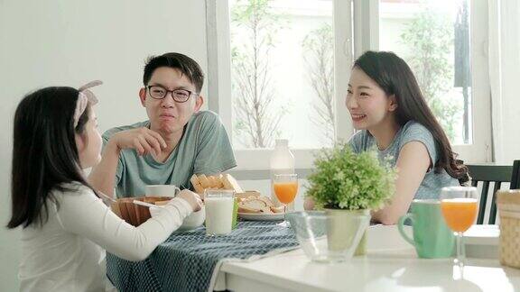 幸福亚洲家庭爸爸妈妈和女儿一起在餐桌上享用早餐的美妙时刻家庭概念