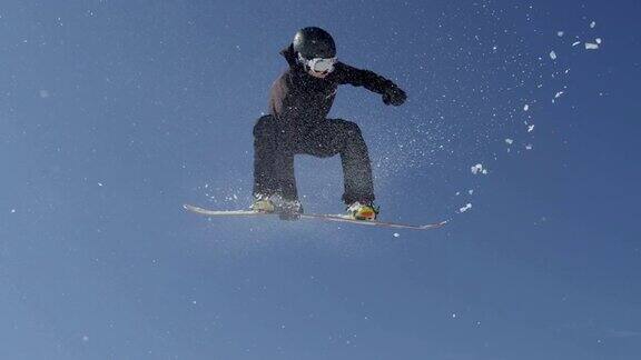 慢动作近景:职业滑雪板跳跃大空中踢滑雪板比赛