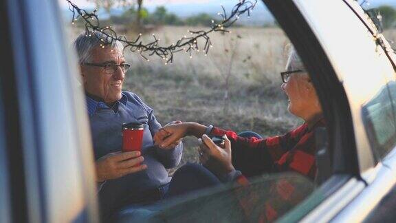一对老年夫妇在徒步旅行前坐在敞篷汽车后备箱里