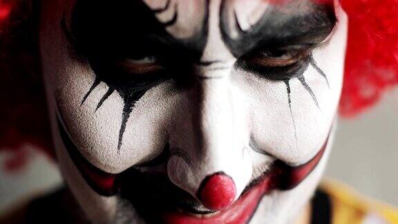 恐怖悲伤的小丑睁开眼睛看着镜头在万圣节脸部特写