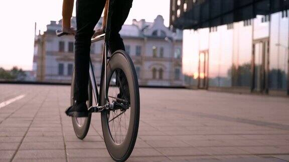 一个穿着红色夹克的骑自行车的人穿过城市经过现代的玻璃建筑