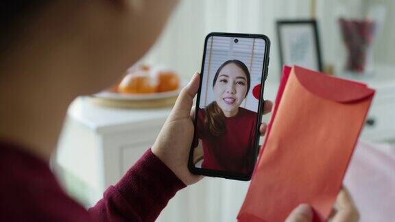 观点自拍视频通话的美丽迷人的年轻亚洲女士在红色春节庆祝服装快乐的微笑交谈和看相机手机祝农历节日