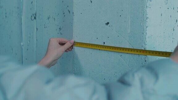 女性手用胶带测量地下室墙壁