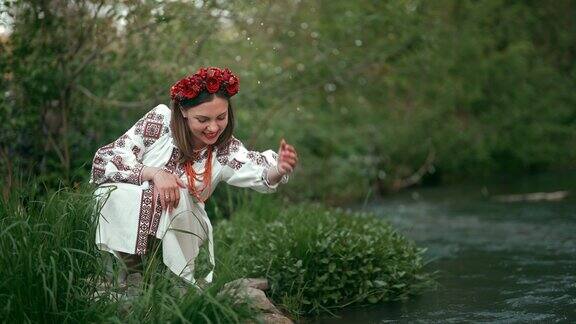 华丽的乌克兰妇女在传统的刺绣vyshyvanka服装坐在河边与森林背景水飞溅乌克兰文化自由民族服饰