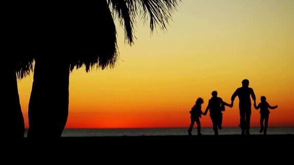 一家人在海边夕阳下的剪影牵着手跑向远方慢动作