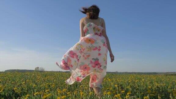 一个女人穿着随风飘动的裙子走在盛开的黄色田野上