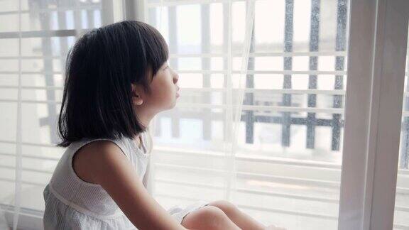 亚洲女孩坐在窗户上孩子望着窗外