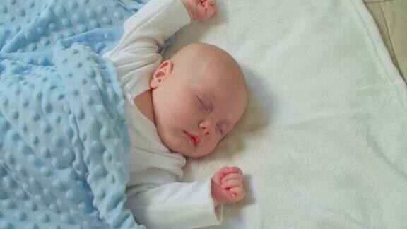 新生婴儿睡在家里房间的床上一个熟睡的孩子男孩在家里睡觉看着梦