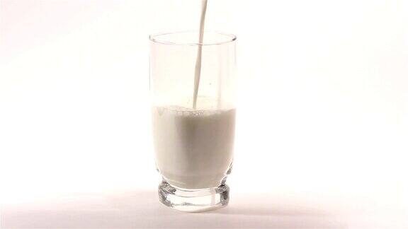 牛奶在白色背景的透明杯中流动