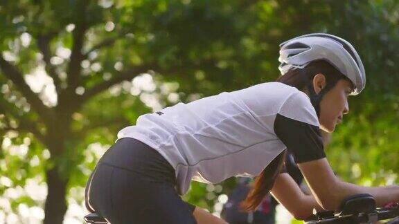 亚洲年轻美丽的女人骑自行车为健康在晚上在公共公园运动员健康和坚定的女孩在运动服装锻炼通过自行车锻炼运动为她的健康健康