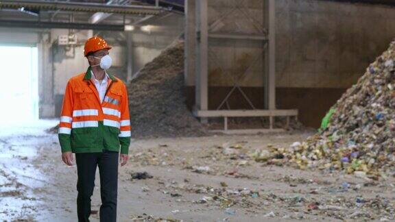 穿着霓虹制服的工人走过回收中心内的一大堆塑料垃圾