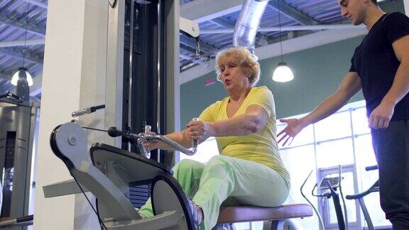 老妇人在健身房里用健身器做引体向上的运动