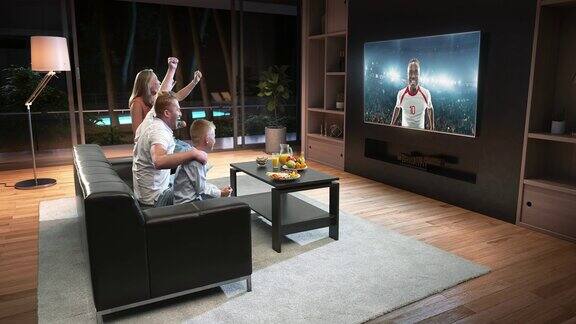 一个家庭正在看电视上的足球时刻庆祝进球