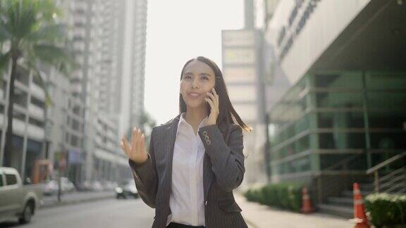 视频缓慢亚洲女人漂亮的女商人白人穿着黑色西装在用智能手机聊天在城市街道的一边