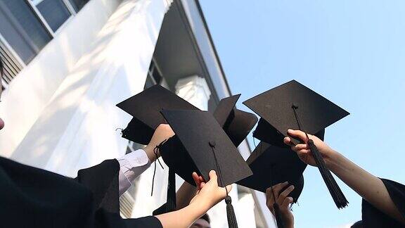 快乐的学生们穿着长袍把学位帽抛向空中教育、毕业与人理念-