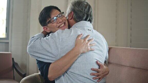 在客厅里年轻的儿子拥抱着他的父亲微笑着慢动作