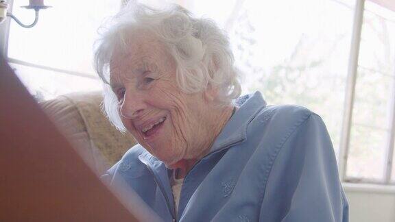 手持拍摄的一个快乐的老年妇女的脸而她是在家里弹钢琴键盘