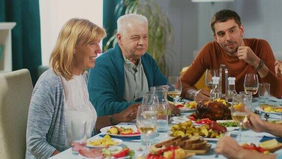 家人和朋友聚在餐桌上老夫妻聊天、开玩笑、吃饭老人和年轻人在开心地笑