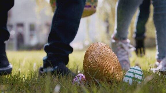 一群寻找复活节彩蛋的孩子跑过花园走向巧克力彩蛋的特写用慢镜头拍摄