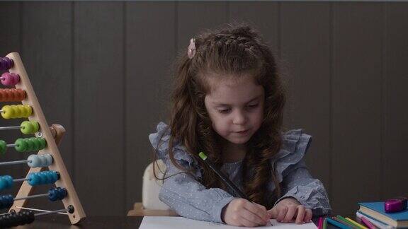 一个小女孩在客厅的桌子上挑选铅笔和做作业