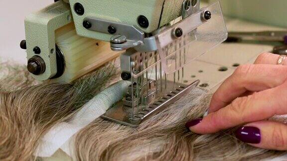 一个女人在缝纫机上缝一顶假发