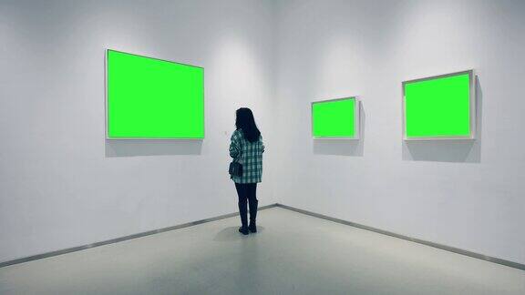 一个年轻的女人在画廊里看绿色的镜框