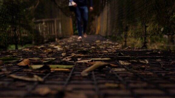 一个人光着脚走过森林中的木桥