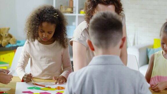 可爱的孩子们在老师的帮助下用彩色纸制作工艺品