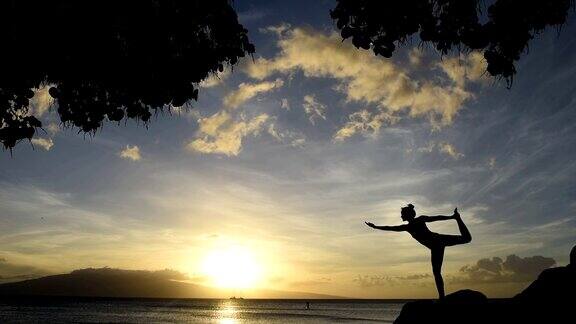 日落时分年轻女子在海边做瑜伽
