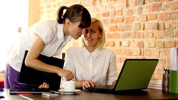 两个年轻的女商人用笔记本电脑指着屏幕用稳定器拍摄
