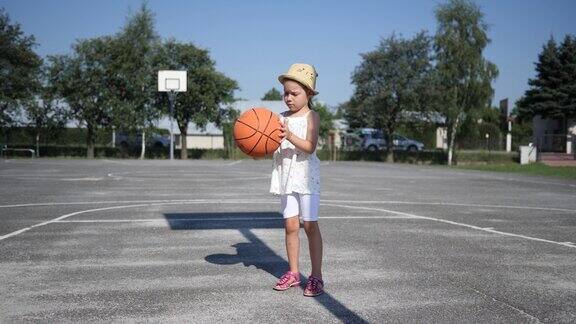 小女孩站在户外操场上打篮球