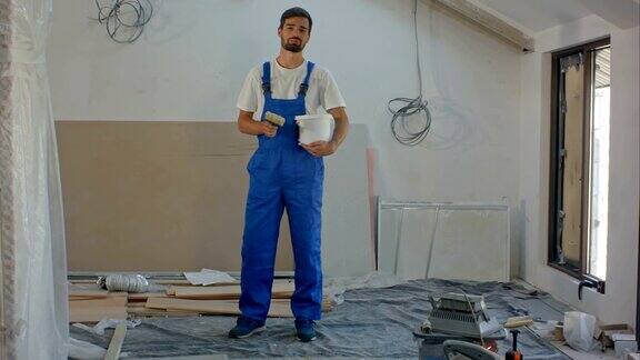 一个年轻的建筑工人对着镜头说话背景是一栋正在施工的房子