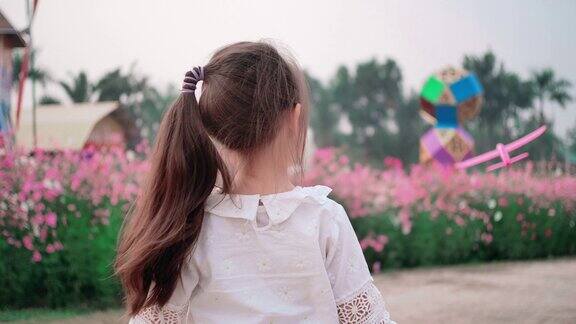可爱的小女孩在美丽的花园里玩玩具飞机