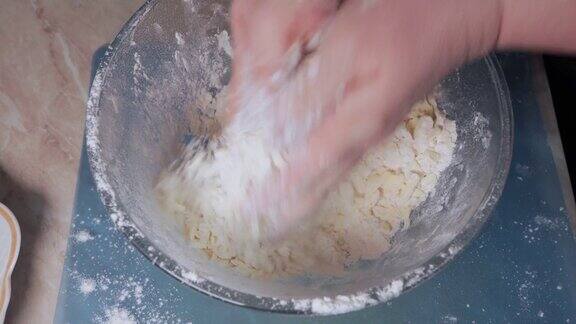 妇女在准备面团做自制饼干时用手混合面粉和黄油