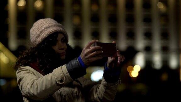 美丽的女士摆姿势和微笑用现代智能手机自拍照片