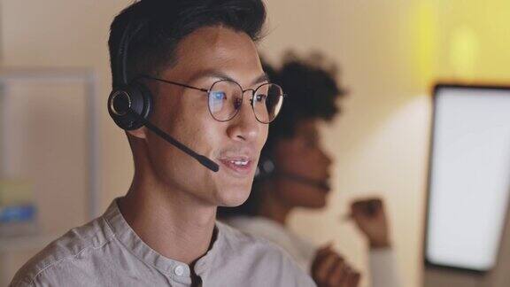 开朗的年轻亚洲男性呼叫中心代理接听电话在办公室工作客服人员打电话并给出建议IT支持人员