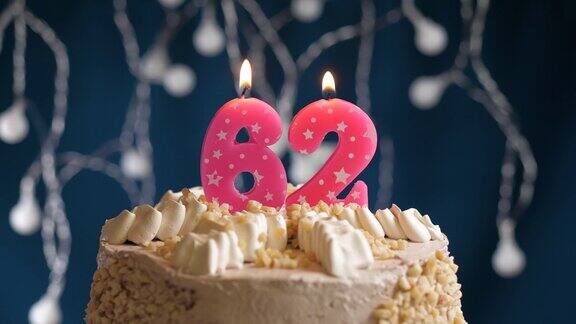 蓝色背景上的62号粉红蜡烛生日蛋糕蜡烛吹灭慢动作和近景