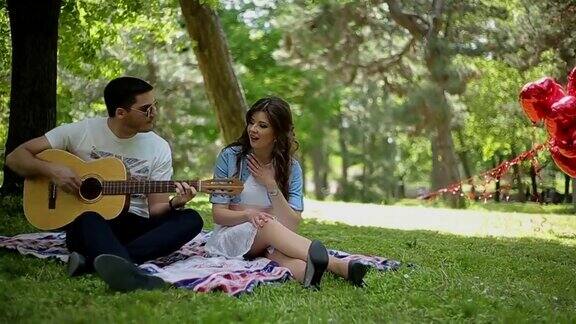 一个男人在野餐时给他的女孩弹吉他