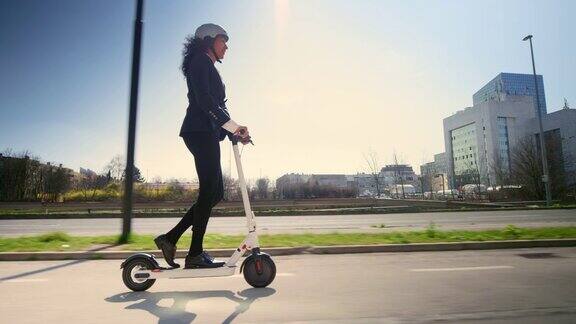 TS女商人在一个阳光明媚的早晨骑着电动滑板车在城市里