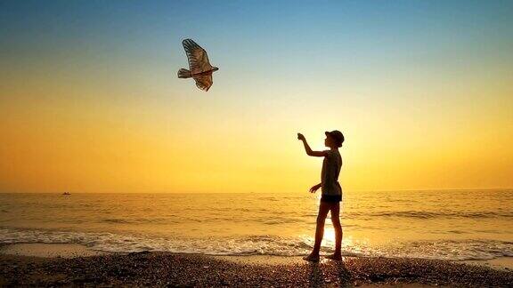 快乐的小男孩在日落的海滩上放风筝慢镜头