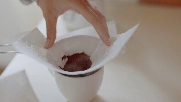 倒入自制过滤咖啡一位妇女将磨碎的咖啡倒入一个纸过滤器