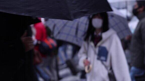 行走在涩谷路口的人们在雨天手持散焦拍摄