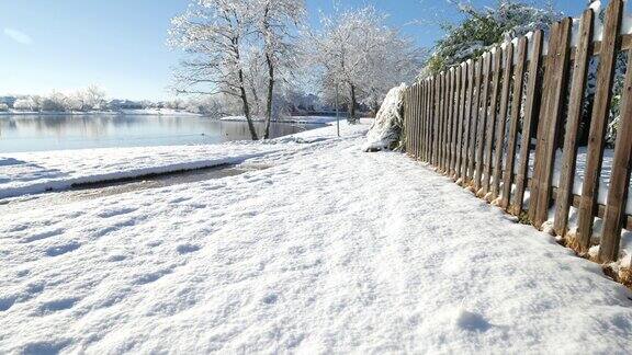 白雪覆盖的地面上有一道木栅栏还有一只鸭子在湖里游泳