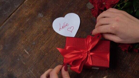 女人用一只红盒子取出一张用手写文字写着爱的明信片打开情人节礼物生日礼物