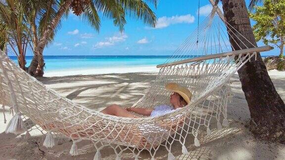 在热带岛屿度假胜地的吊床上休息的女人
